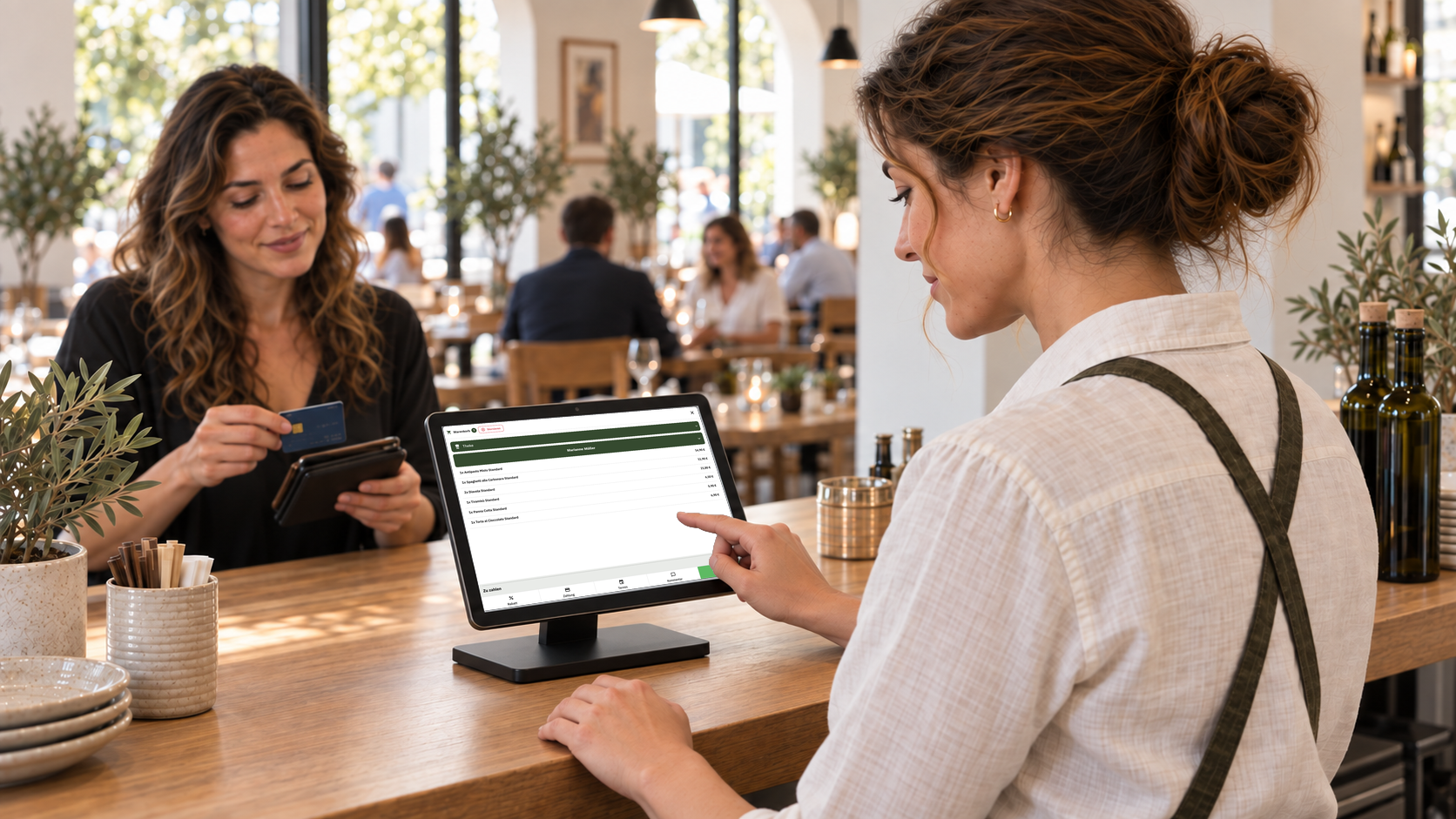 A member of staff uses the tablet POS while a customer at the counter has her card ready.